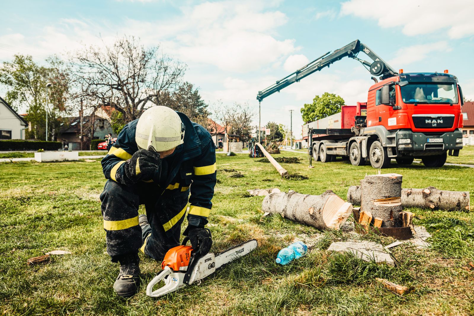 Arborist with a chainsaw working beside a crane truck